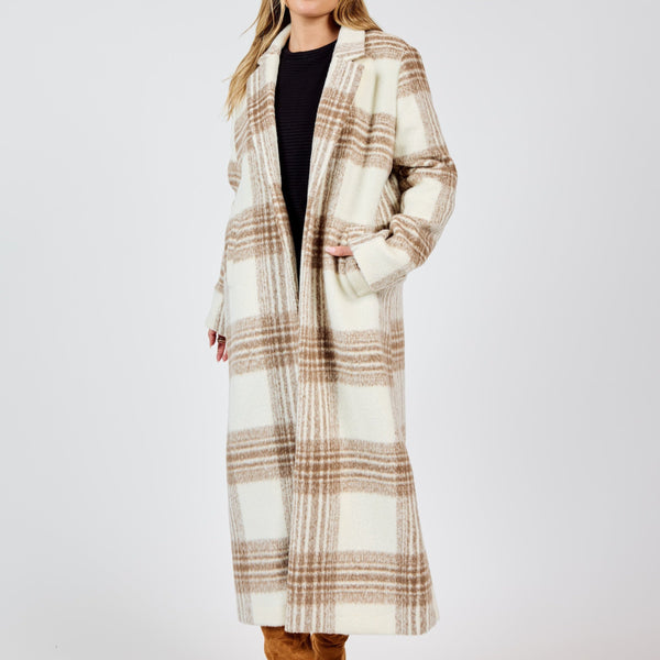 front view of the model wearing the zella plaid buttoned long coat. shows the full length of the coat. also shows the pockets, the collar and the one button closure. 