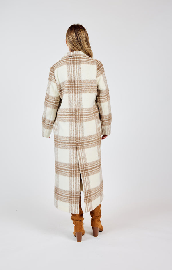 back view of the model wearing the zella plaid buttoned long coat. shows the back slit. also shows the pockets and the long length. 