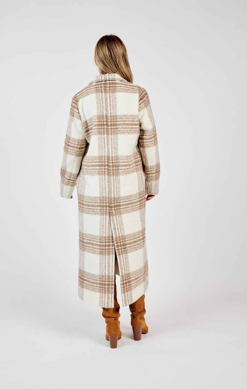 back view of the model wearing the zella plaid buttoned long coat. shows the back slit. also shows the pockets and the long length. 