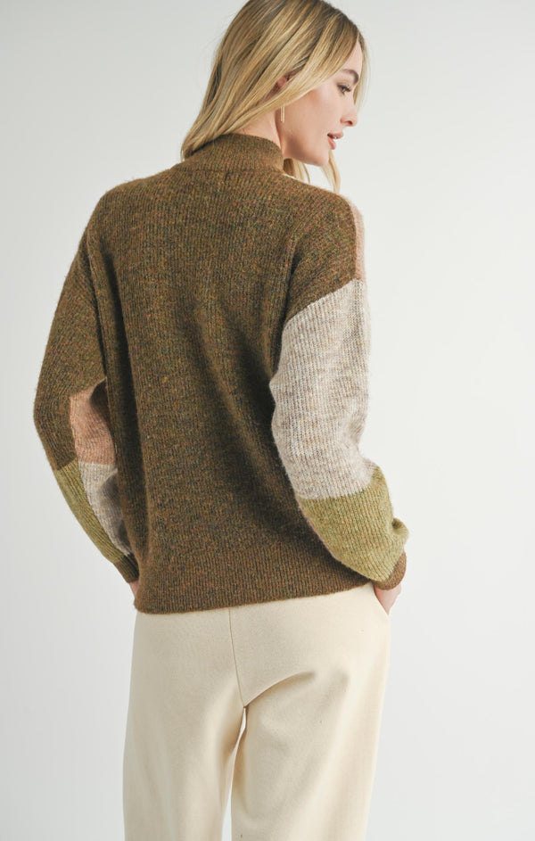 back view of the model wearing the forest walk turtleneck sweater. shows the dropped shoulders. also shows the ribbed detailing, the multi coloring throughout and the slight oversized. 