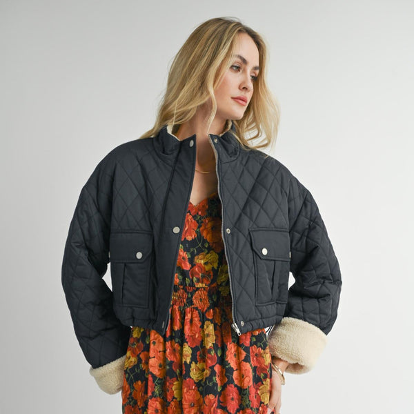 front view of the model wearing the ashton quilted jacket. shows the front patch pockets. also shows the sherpa cuffs, the zipper closure and the front patch pockets. 