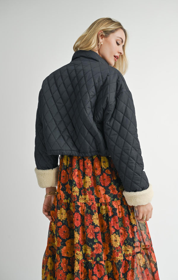 back view of the model wearing ashton quilted jacket. shows the cropped length. also shows the sherpa cuffs and the quilted detailing.