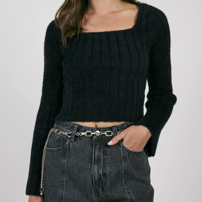 front view of the model wearing the camille square neck sweater in black. shows the square neckline. also shows the cropped length, the long sleeves and the ribbed detailing. 