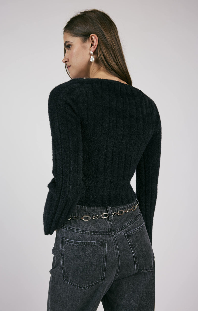 back view of the model wearing the camille square neckline sweater. shows the long sleeves. also shows the black color, the ribbed detailing and cropped length. 