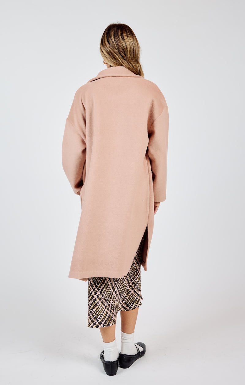 back view of the model wearing the hayley open coat in this rose color. shows the side slits. also shows the collar and the mid length. 