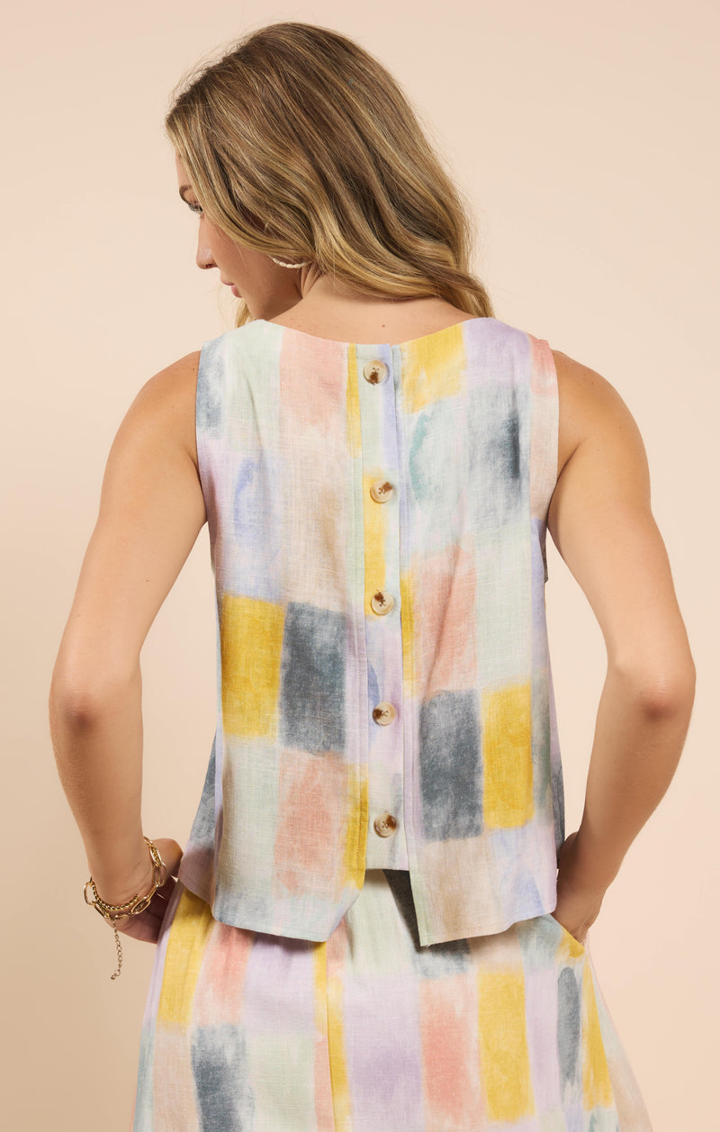 back view of the model wearing the petrichor sleeveless top. shows that the top is sleeveless. also shows the back button down detail, and the multicolor block pattern. 