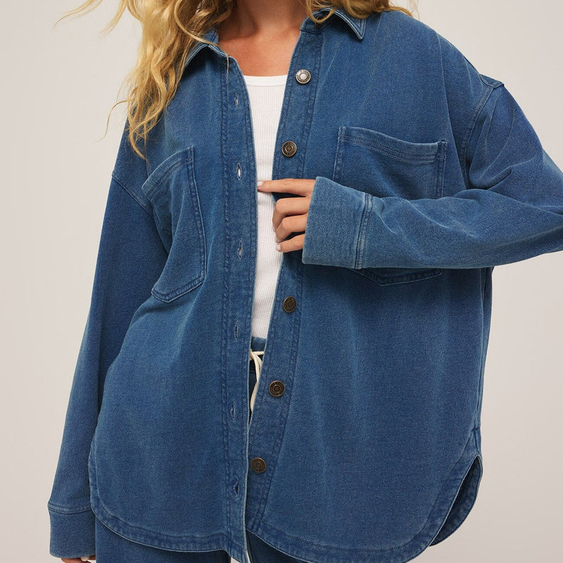 front view of the model wearing the all day knit denim jacket. shows the front patch pockets. also shows the button down front closure, the curved bottom hem, the collar and the oversized fit. 