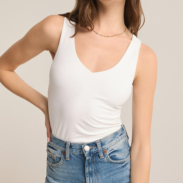front view of the model wearing the avala v neck so smooth top in white. shows that the top is sleeveless. also shows the soft v neckline and thats its fitted and tuckable. 