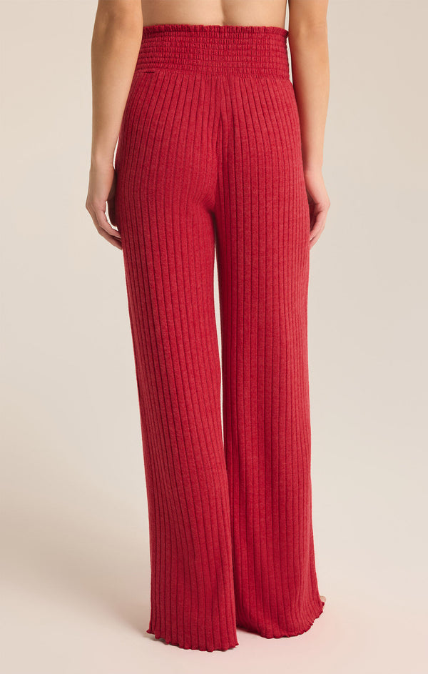 back view of the model wearing the dawn smocked rib pant. shows the high waist. also shows the red color, the smocked waist, the ribbed detailing and the wider leg. 