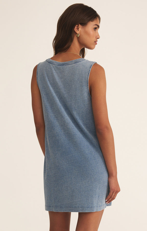 back view of the model wearing the sloane v neck knit denim dress. shows the dress is sleeveless. also shows the denim mineral wash, the relaxed fit and the mid thigh length. 