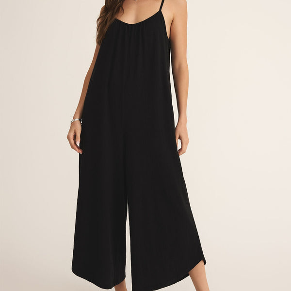 front view of the model wearing the selena  textured flare jumpsuit. its a pull on style. also shows the skinny straps, the cropped, ankle fit and the color of the jumpsuit which is black. 